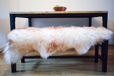 a bench made out of sheepskin with a bowl on the table in the background