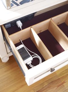 an open drawer with two cell phones in it and cords plugged into the drawers