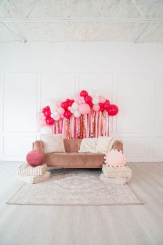 a living room filled with furniture and lots of pink balloons on the wall above it