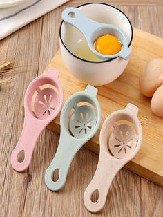 three egg slicers sitting on top of a cutting board next to an egg in a bowl