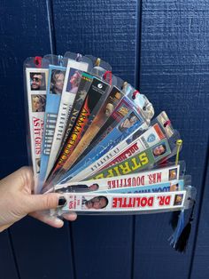 a person holding up a bunch of magazines in front of a blue wall and door