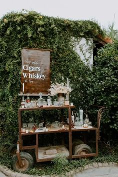 an old fashioned cart with bottles and glasses on it sitting in front of a building