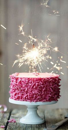 a cake with pink frosting and sparklers on top