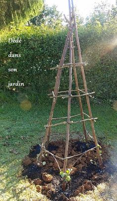 a wooden tower made out of sticks and dirt in the grass with words above it