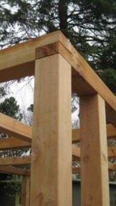 an unfinished wooden structure in front of some trees