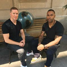 two men sitting on a bench in front of a building with a globe behind them