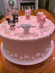 a pink cake with white frosting and little animals on top