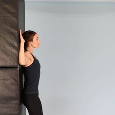 a woman in black shirt and leggings leaning against wall