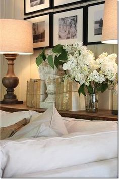 a bed with white sheets and flowers in vases