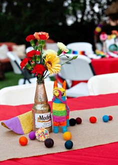 a table topped with a vase filled with flowers next to a stuffed animal and candy