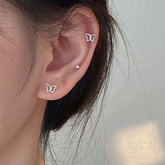 a close up of a person's ear with two small butterfly studs on it