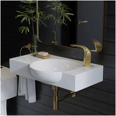 a white sink sitting under a mirror next to a toilet and a plant in a vase