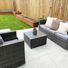 an outdoor seating area with grey wicker furniture and green grass in the back yard