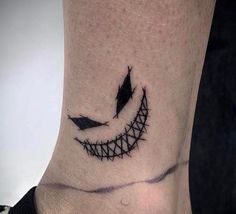 a black and white photo of a smile face tattoo on the ankle, with lines coming out of it