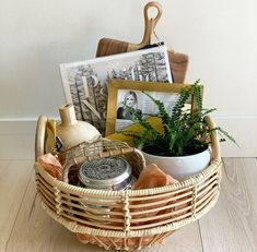 a basket filled with plants and pictures on top of a wooden floor