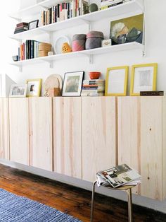 a living room with bookshelves and pictures on the wall above it, along with a blue rug