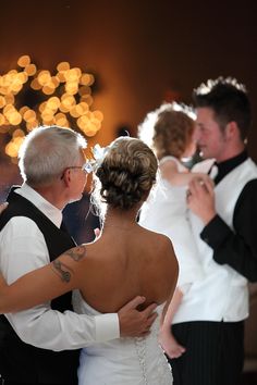 the bride and groom are dancing together at their wedding reception with lights in the background