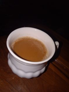 a cup of coffee sitting on top of a wooden table