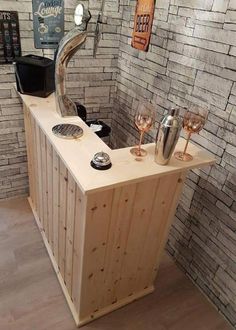 a wooden counter with wine glasses on it in front of a brick wall and sign