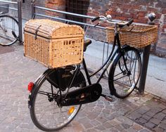 a bicycle with a basket on the back parked next to a brick wall and fence