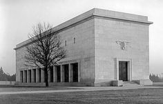 an old black and white photo of a building with columns on the outside, trees in front of it