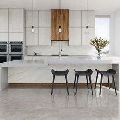 three chairs are sitting in front of an island counter with two ovens and a sink