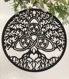 a circular metal wall hanging with an intricate tree design