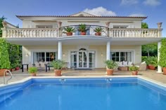 a house with a swimming pool in front of it and some plants on the balcony