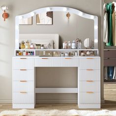 a white dressing table with lights on top and drawers in front of it, next to a mirror