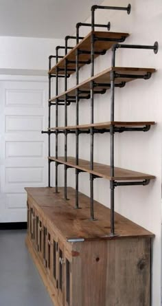 a wooden shelf with metal pipes and shelves on the wall next to a white door