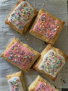 four cookies with white frosting and sprinkles