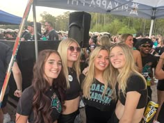 some pretty young ladies standing next to each other in front of a group of people