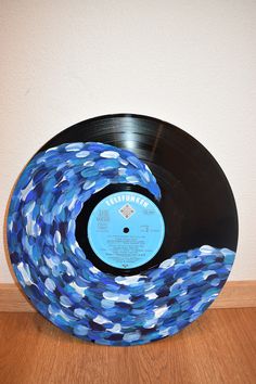 a vinyl record with blue and white confetti on it sitting on a wooden floor