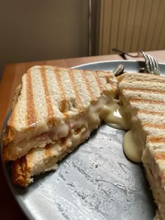 a grilled cheese sandwich is cut in half on a plate with a fork and knife