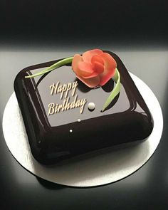 a black and white birthday cake with a flower on the top that says happy birthday