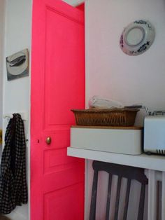 a bright pink door in the corner of a room with a basket on top of it