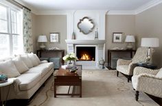 a living room filled with furniture and a fire place in front of a mirror on the wall