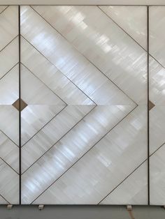 a white cabinet with geometric designs on the front and back doors, in an empty room