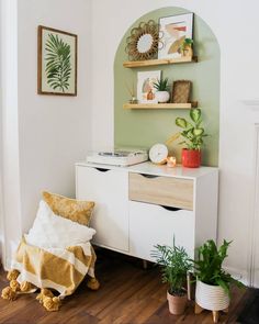 a living room with some plants on the wall and a white dresser next to it