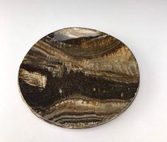 a black and white plate sitting on top of a white table next to a wall