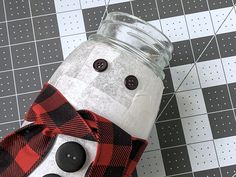 a snowman made out of a mason jar on a tiled floor with black and white tiles