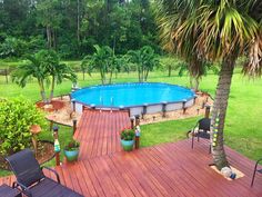 an above ground pool surrounded by trees and lawn furniture with chairs around it on a wooden deck