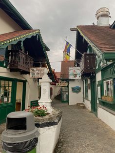 an alley way with buildings and flags on the top of each building, including a clock tower