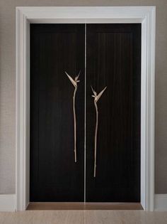 two tall wooden doors with metal handles in a room that has beige walls and wood flooring