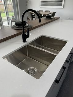 a kitchen sink sitting under a faucet next to a counter top in front of a window