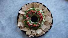 a black plate topped with tortilla chips and a wreath shaped ring on top of it