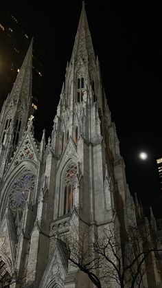 an old cathedral lit up at night with the moon in the background