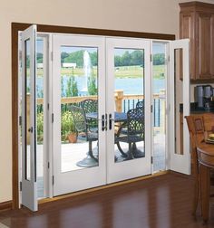 an open patio door leading to a deck overlooking a lake and picnic table with chairs