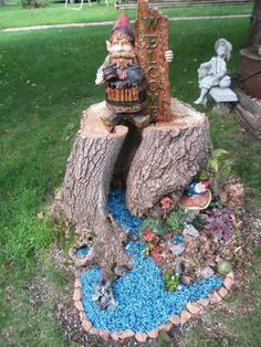 a tree stump with a statue on top of it in the middle of a yard