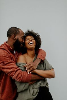 a man and woman embracing each other with their arms around one another as they laugh